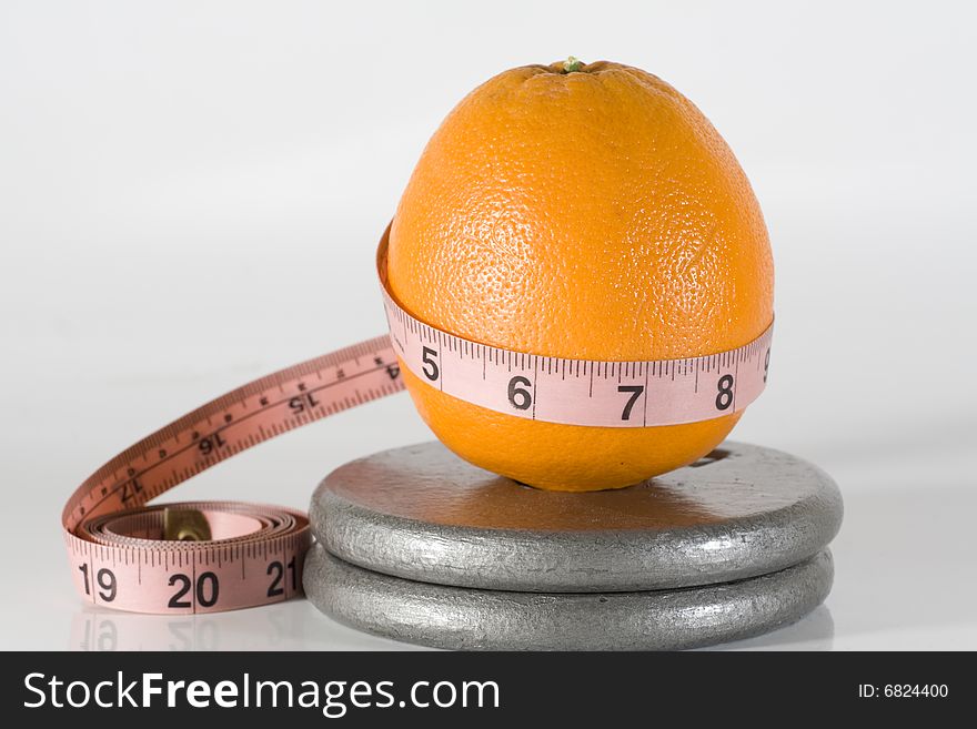 Orange with a measuring tape aound it by weights. Orange with a measuring tape aound it by weights.