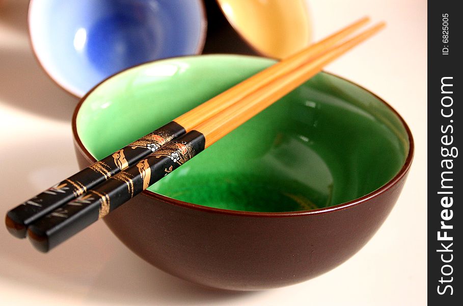 Three different colored bowls and chopsticks