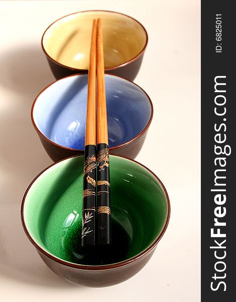 Three different colored bowls and chopsticks