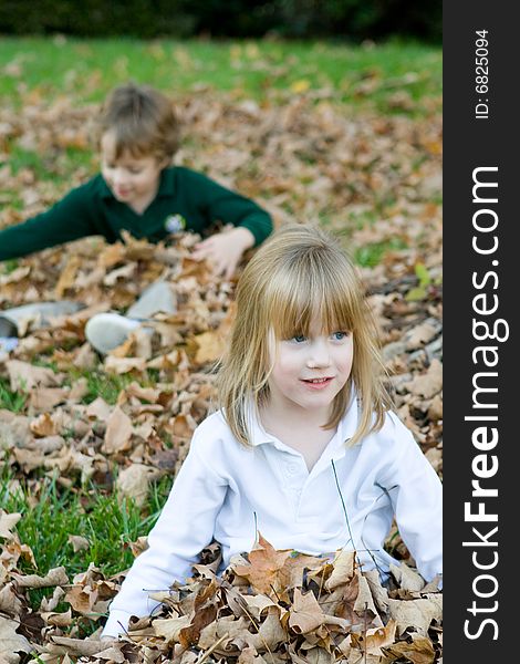 A set of boy girl twins playing in the autumn leaves