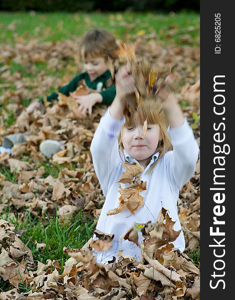 A set of boy girl twins playing in the autumn leaves