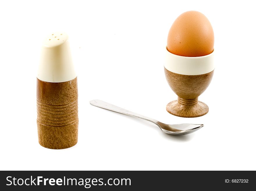 A soft boiled egg, a spoon and a saltpot