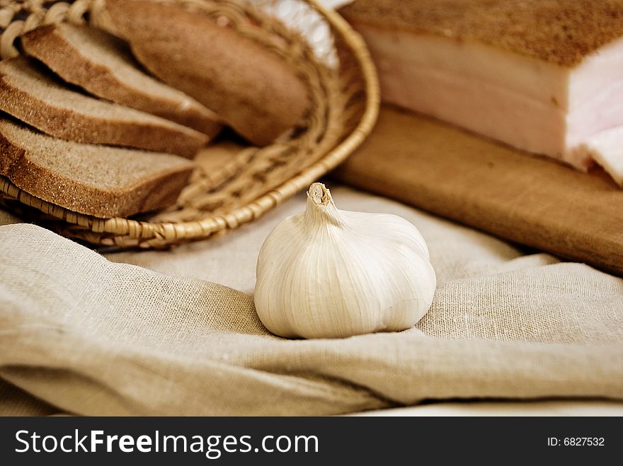 Garlic in focus, bread and bacon as background