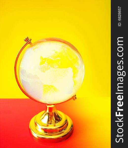 Glass globe of the world on colored background