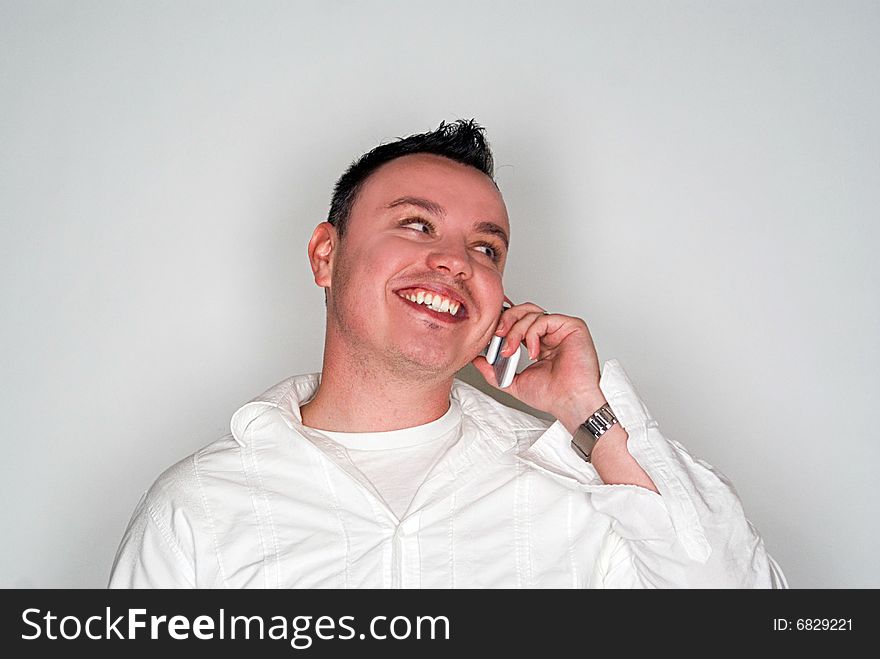 A young man having a conversation on a white cell phone.