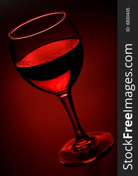 Glass of red wine over red background