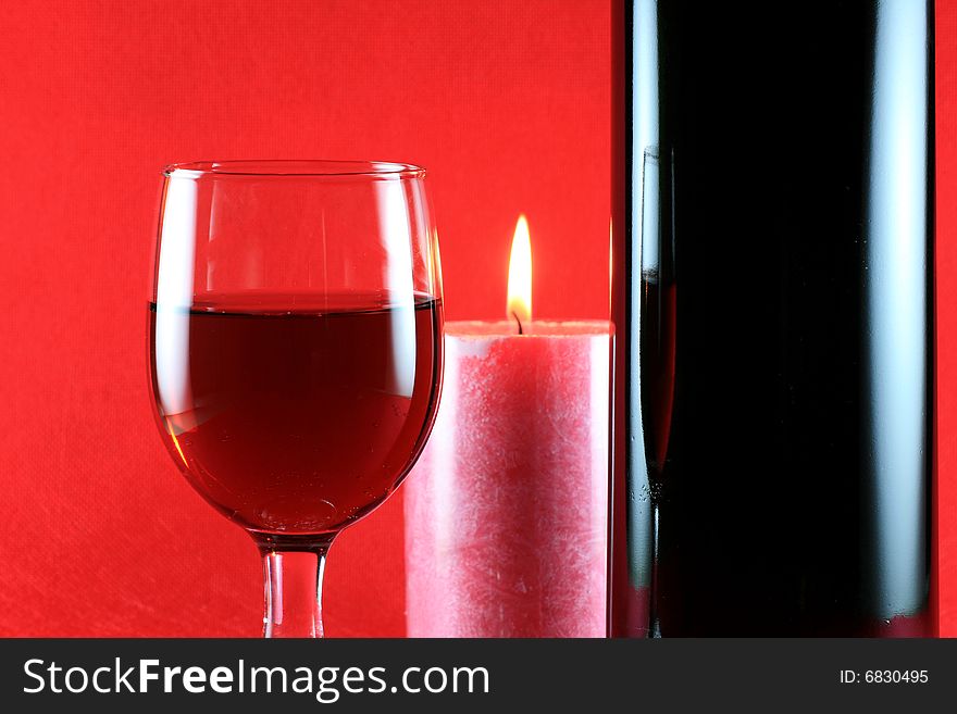 Wineglass with Candle & Wine Bottle on Red Background