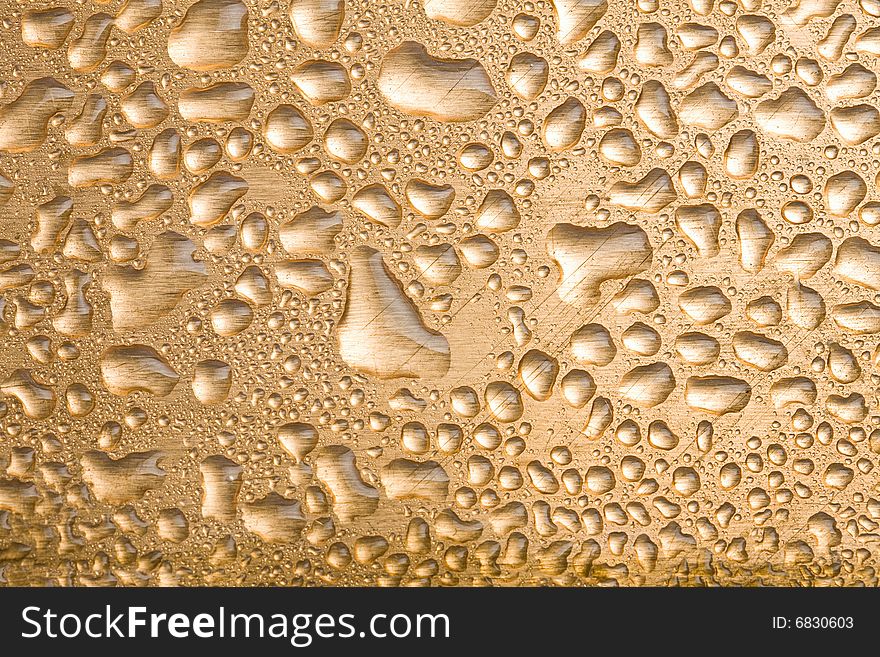 Golden water drops over brushed metal background. Golden water drops over brushed metal background