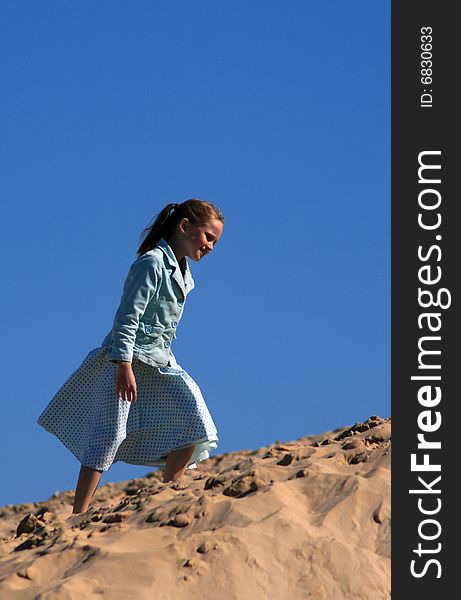 A white caucasian girl child playing on a sand dune on a hot summers day. A white caucasian girl child playing on a sand dune on a hot summers day