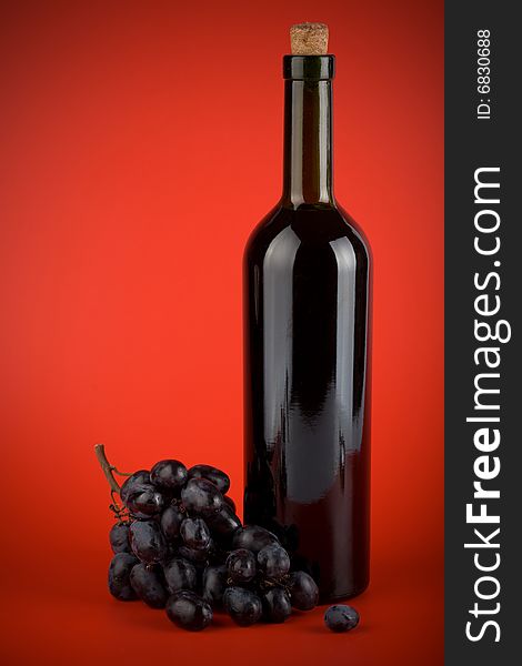 Bottle Of Wine And Grapes Over Red Background