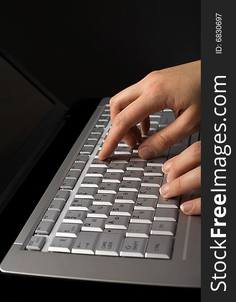 Fingers over notebook keyboard over black background