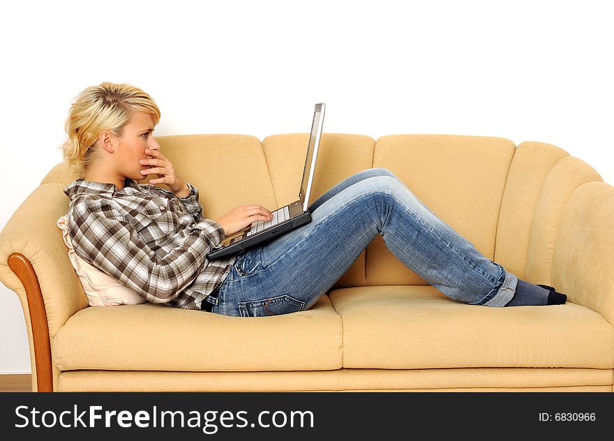 Young woman working with her laptop, sitting on a sofa. Young woman working with her laptop, sitting on a sofa.