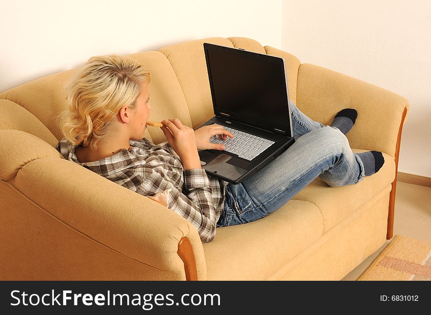 Young woman working with her laptop, sitting on a sofa. Young woman working with her laptop, sitting on a sofa.