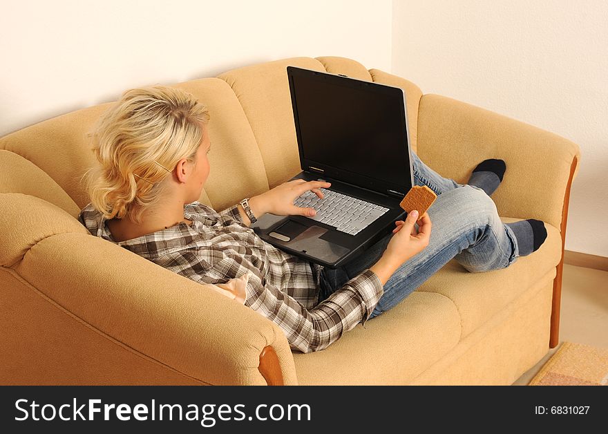 Young woman working with her laptop, sitting on a sofa. Young woman working with her laptop, sitting on a sofa.