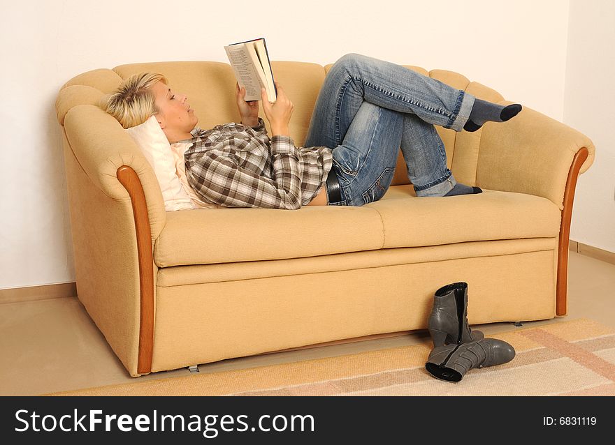 Young woman reading a book, lying on a sofa. Young woman reading a book, lying on a sofa.