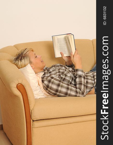 Young woman reading a book, lying on a sofa. Young woman reading a book, lying on a sofa.