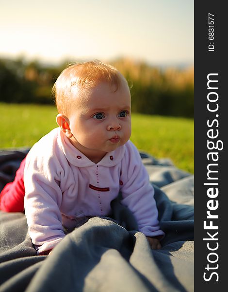 Baby of 6 months is crawling outside on the grass with big cheeks. Baby of 6 months is crawling outside on the grass with big cheeks