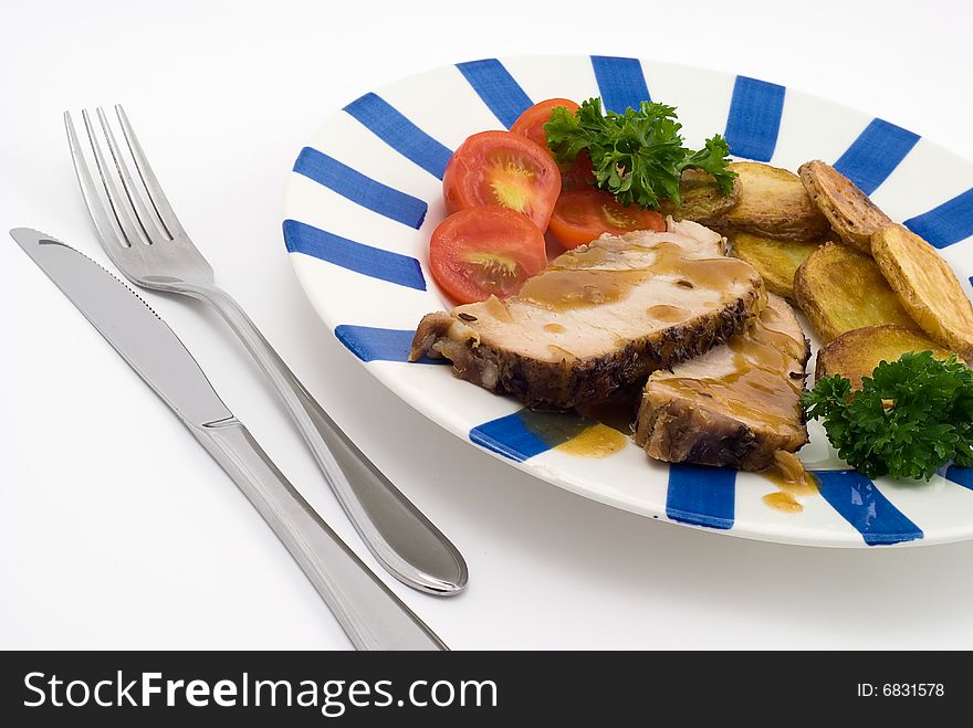 Roasted pork with potatoes, tomatoes and fresh green parsley