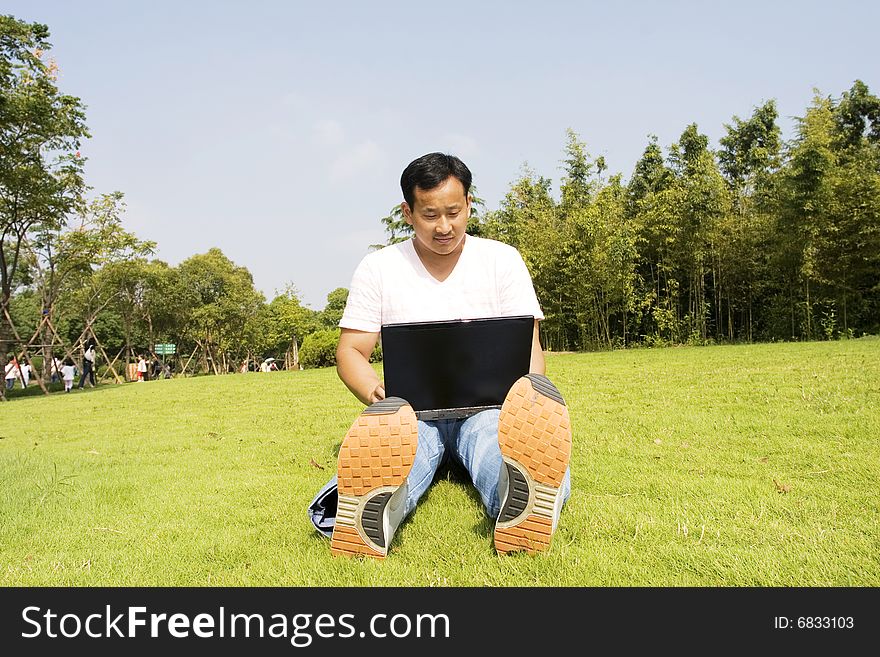 A young man using a laptop outdoors