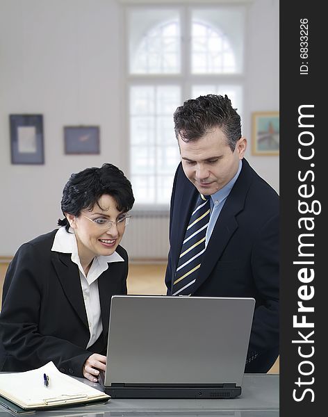 Young smiling businessman and a businesswoman working together with a laptop. Young smiling businessman and a businesswoman working together with a laptop