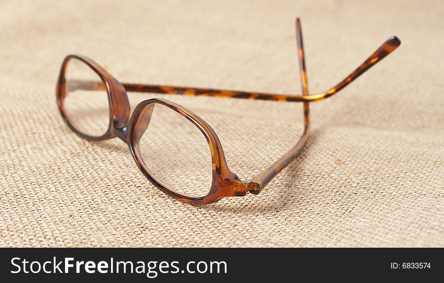 Brown horn-rimmed glasses on mesh material. Shallow depth of field. Brown horn-rimmed glasses on mesh material. Shallow depth of field