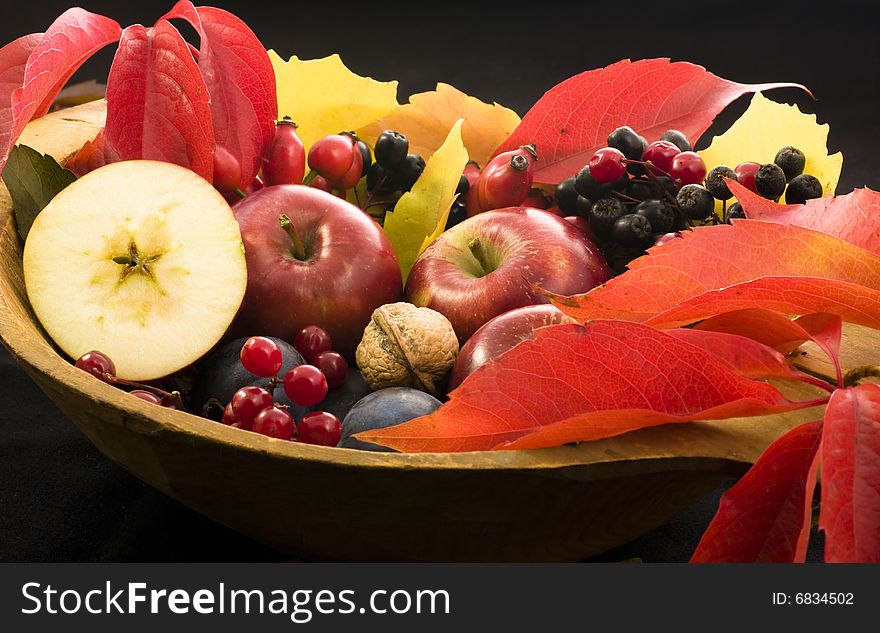 A basket of multi-colored leaves  with apples. A basket of multi-colored leaves  with apples