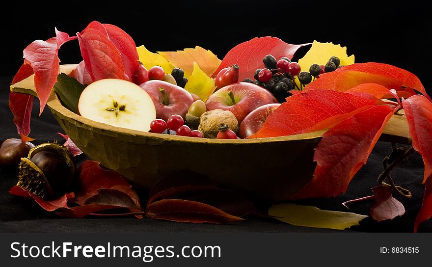 A basket of multi-colored leaves with apples. A basket of multi-colored leaves with apples