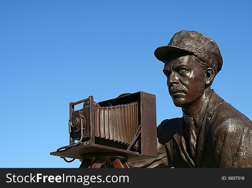 A Statue of a photographer using a Korona-V vintage camera to take a photograph. A Statue of a photographer using a Korona-V vintage camera to take a photograph.