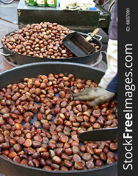 Vendors roasting chestnuts in a market in Bolzano, Italy. Autumnal season. Vendors roasting chestnuts in a market in Bolzano, Italy. Autumnal season.