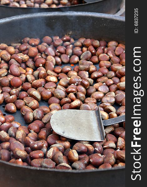 Vendor roasting chestnuts in a market in Bolzano, Italy. Autumnal season. Vendor roasting chestnuts in a market in Bolzano, Italy. Autumnal season.