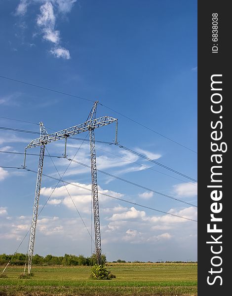 Big metal power line pole in the field over the beautiful cloudscape.