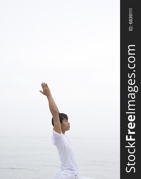 A young man practicing yoga at the beach. A young man practicing yoga at the beach
