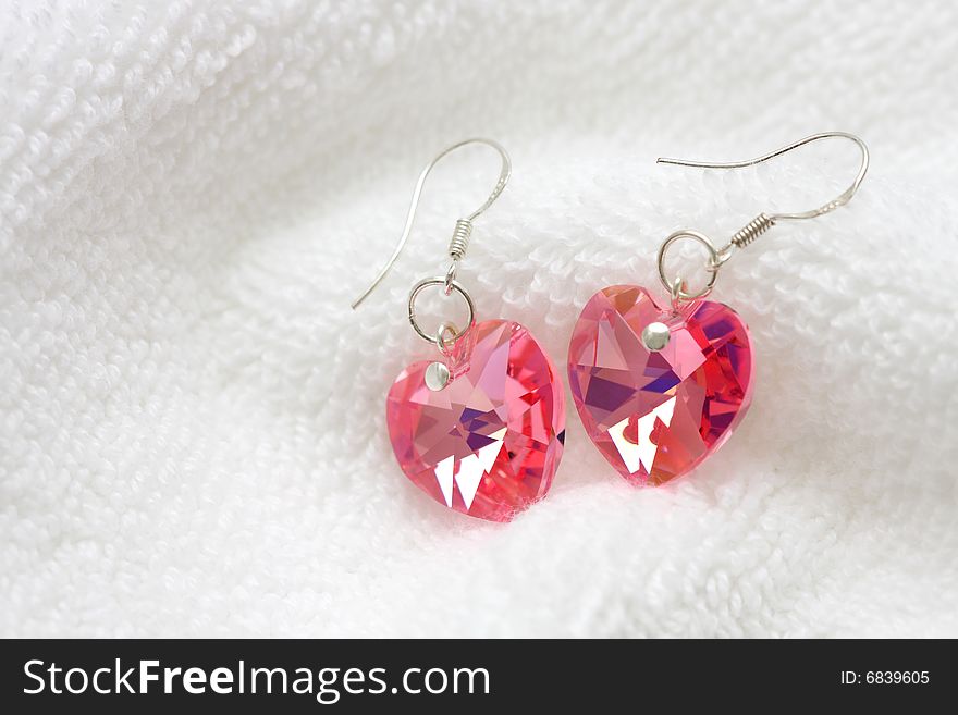 A pair of pink earrings put on white cotton cloth.