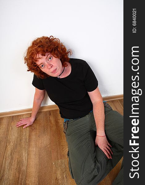 Red head woman at home sitting on wooden floor. Red head woman at home sitting on wooden floor