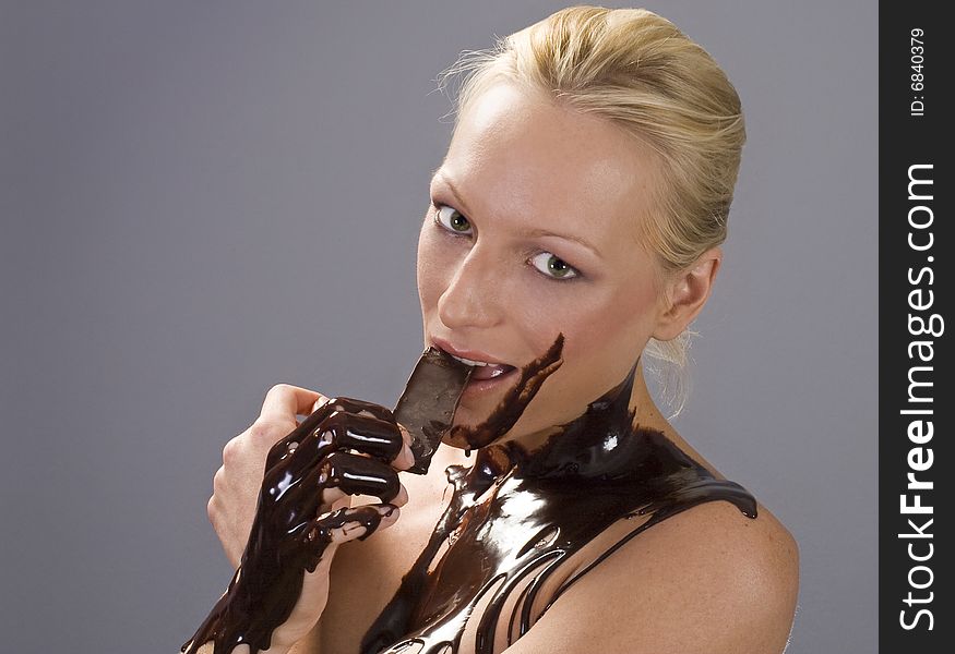 Beautiful naked blond girl eating chocolate with melted chocolate all over her. Beautiful naked blond girl eating chocolate with melted chocolate all over her