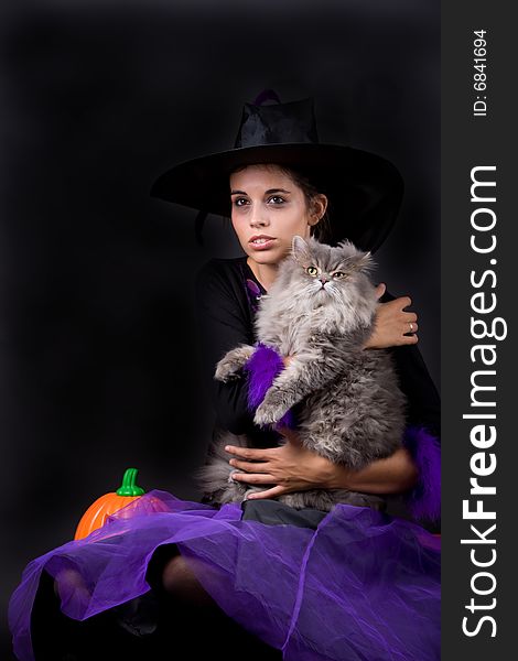 Young halloween witch with grey cat