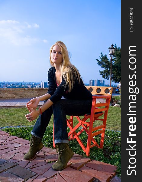 Beautiful blondy sitting on red chair ad ejoy in sun