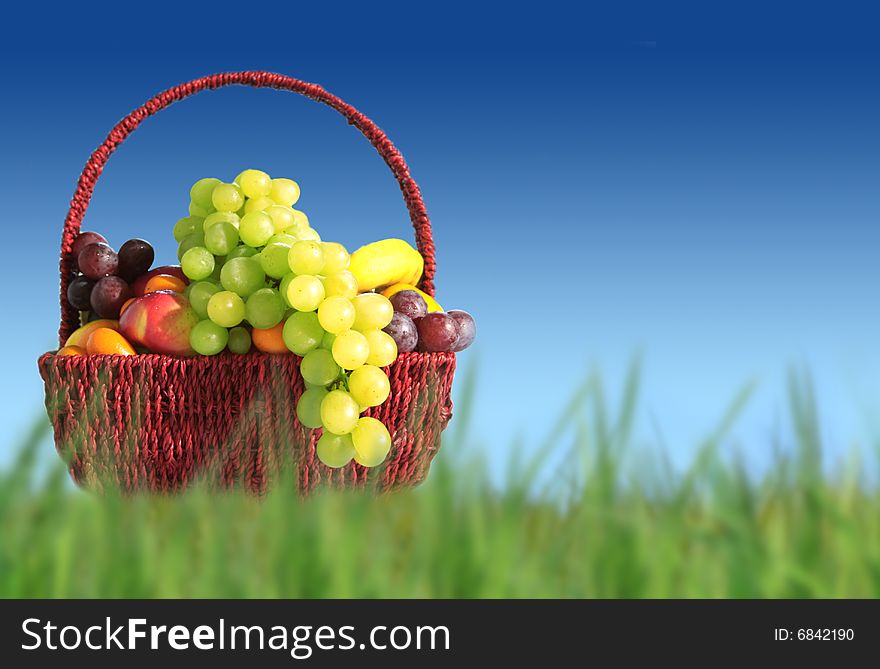 Fruits in a basket on blue sky background. Copy space for text.