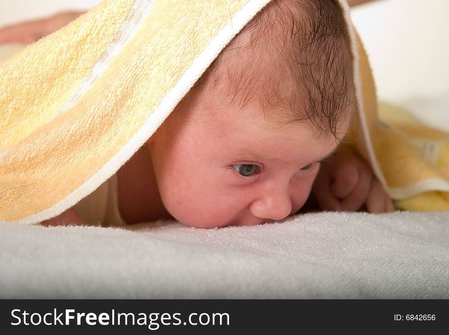 Newborn baby under towel spying on surrounding world