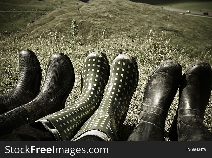 Three rubber rain boot Wellies lined up on grassy lawn. Three rubber rain boot Wellies lined up on grassy lawn