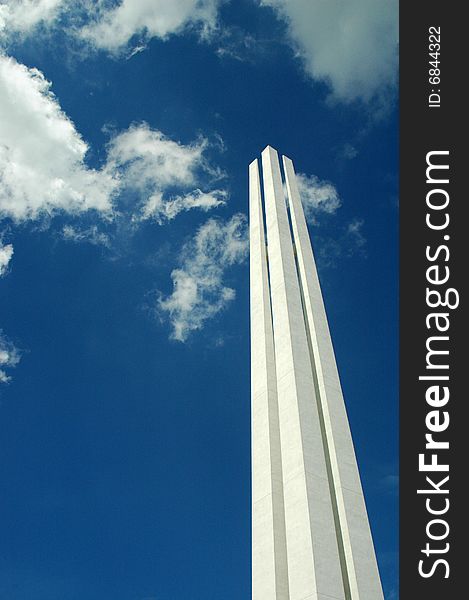The top of Singapore War Memorial monument that look like a pair of chopsticks in a blue sky, white clouds backdrop