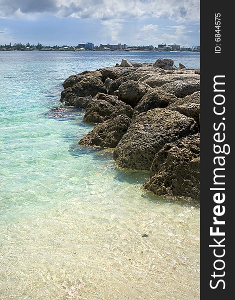 Tropical beach with rocks extending into the ocean.