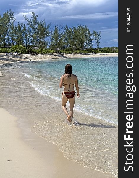 Young woman walking down a beautiful tropical beach. Young woman walking down a beautiful tropical beach.