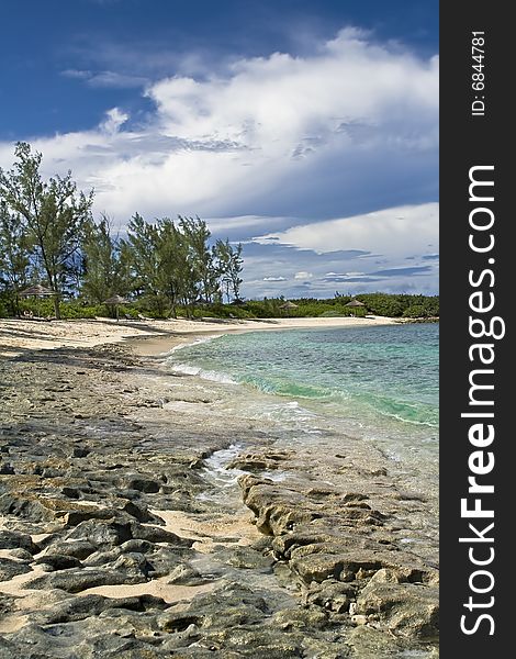 Tropical shoreline with clear green water and rocky shoreline.