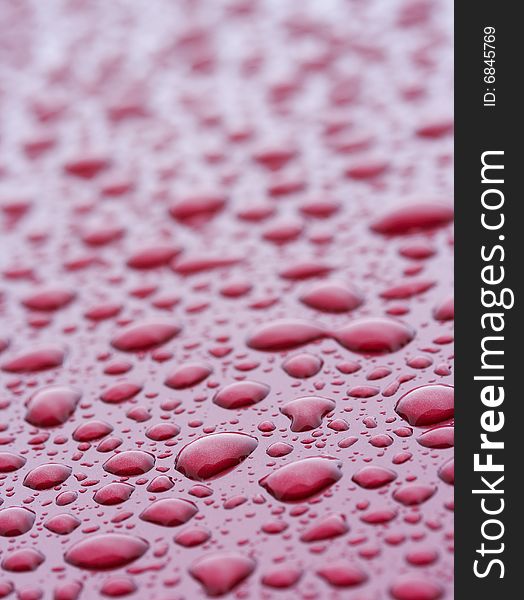 A picture of water drops on a red metal surface. A picture of water drops on a red metal surface