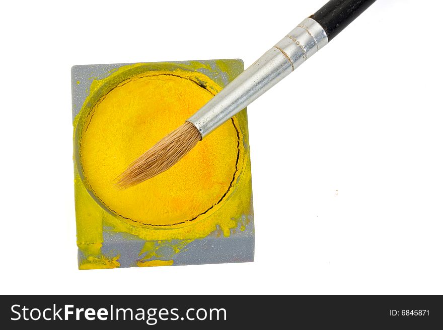 A brush and a yellow watercolor tin isolated on white