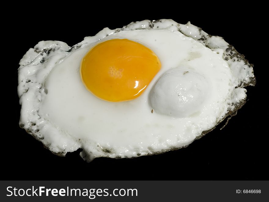 A shot of a fired egg isolated on black. A shot of a fired egg isolated on black