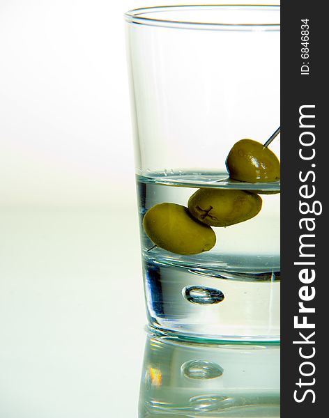 A shot of a Drink with some olives. A shot of a Drink with some olives