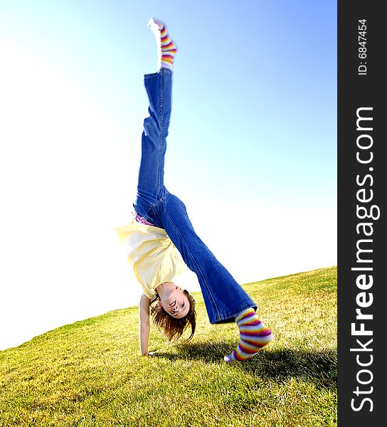 Young girl doing cartwheel across green grass. Young girl doing cartwheel across green grass