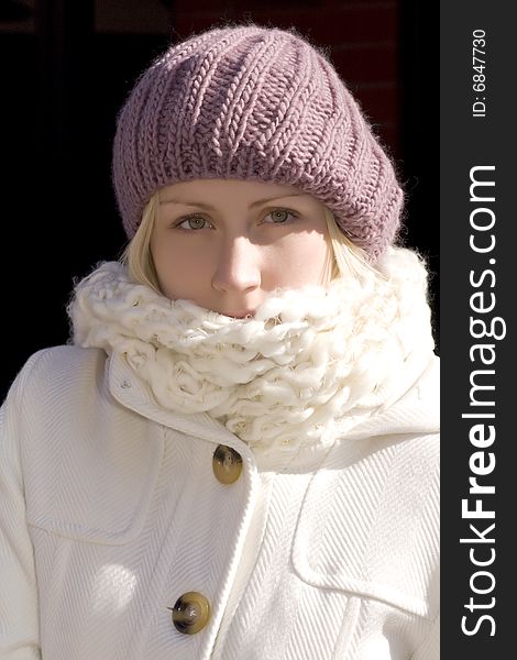 Attractive young blonde woman wearing magenta knit hat, white knit scarf and winter coat. Attractive young blonde woman wearing magenta knit hat, white knit scarf and winter coat.